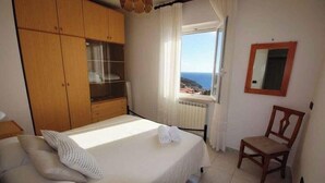Una camera da letto con un letto, un'armadiatura in legno, una sedia, una finestra con vista e uno specchio a parete.