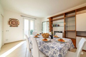 Zona pranzo con tavolo apparecchiato per due, una libreria e un elemento decorativo a parete.