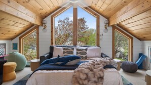 A cozy bedroom with a large bed, a window, and a wooden ceiling. - The Apex at Moody: Sun-Filled Beach House (Wells)