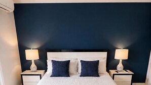 A neatly arranged bedroom with a large bed, two bedside tables with lamps, and a black rug.