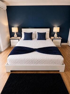 A neatly arranged bedroom with a large bed, two bedside tables with lamps, and a black rug.