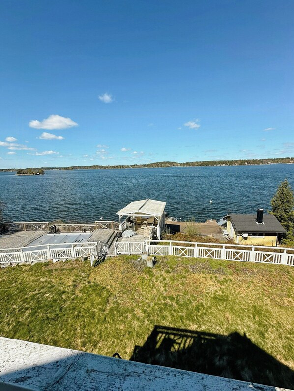 A lakeside property with a dock, a covered seating area, and a small building.