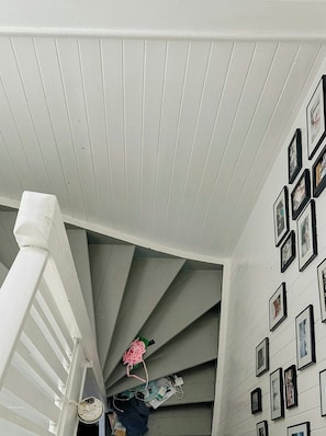 A staircase with white railings and a wall adorned with framed pictures.