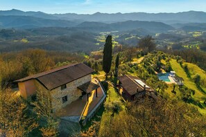 A stone house with a tiled roof, surrounded by a well-maintained garden and a swimming pool. - Panoramic villa with pool in Lunigiana (Fivizzano)