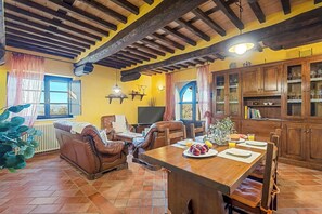 Un intérieur rustique avec une table à manger, des fauteuils en cuir, un téléviseur et des meubles en bois.