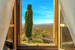 A view through an open window with a tall tree and a distant landscape. - Panoramic villa with pool in Lunigiana (Fivizzano)