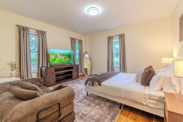 Ein Schlafzimmer mit Bett, Sofa, Fernseher und Spiegel.