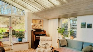 Una habitación acogedora con un piano, un sillón mullido, un sofá azul y una mesa.