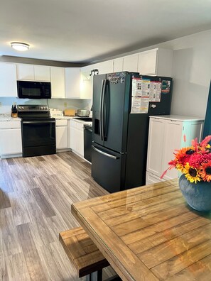 Una cocina moderna con armarios blancos, un refrigerador negro, un microondas y una estufa.