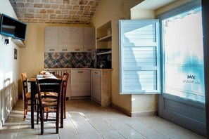 A kitchen with a dining table, chairs, cabinets, and a TV. - Restored trullo with pool near Alberobello (Martina Franca)