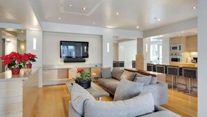 Una sala de estar moderna con un sofá, un televisor de pantalla plana y una zona de cocina con barra.