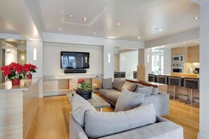 Ein modernes Wohnzimmer mit einer Couch, einem Flachbildfernseher und einer Küchenzeile mit Bar.