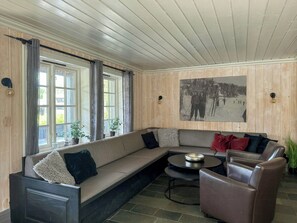 Een moderne woonkamer met een hoekbank, een ronde salontafel en een aan de muur hangend schilderij.