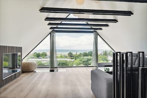 Ein modernes Interieur mit einem großen Fenster, einer Couch, einem Fernseher und Holzboden.