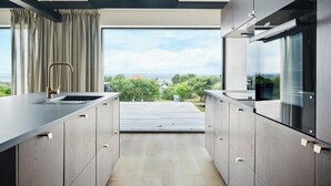 Une cuisine moderne avec vue sur l’extérieur, dotée d’appareils électroménagers intégrés et d’un design épuré.