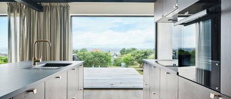 A modern kitchen with a view of the outdoors, built-in appliances, and a sleek design.