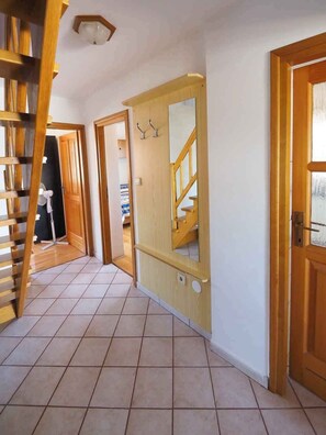 Ein Korridor mit Holztüren, einer Treppe und einem Fliesenboden.