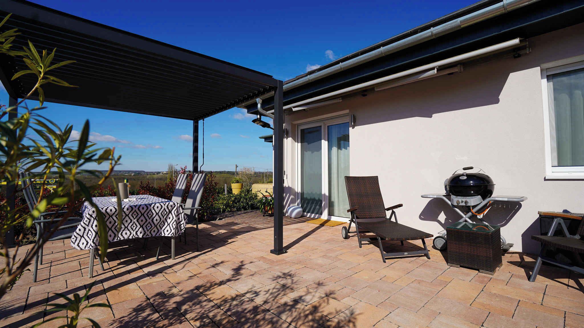 A patio with outdoor furniture, a grill, and a covered area.