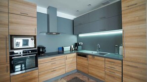 A modern kitchen with built-in appliances, a central island, and a large window.