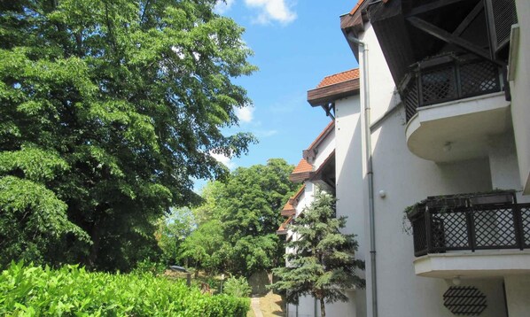 Ein Gebäude mit Balkon, umgeben von üppigem Grün und Bäumen.