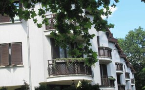 Ein mehrgeschossiges Gebäude mit Balkonen, einer weißen Fassade und einem Gittermuster an den oberen Balkonen.