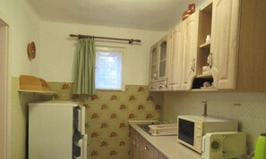A compact kitchen with a refrigerator, a microwave, and wooden cabinets.