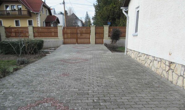 A paved driveway leading to a gated entrance, surrounded by residential buildings.