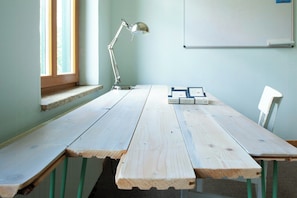 Ein Holztisch mit Bänken, einer Schreibtischlampe und einer Tafel in einem Raum mit hellblauen Wänden.