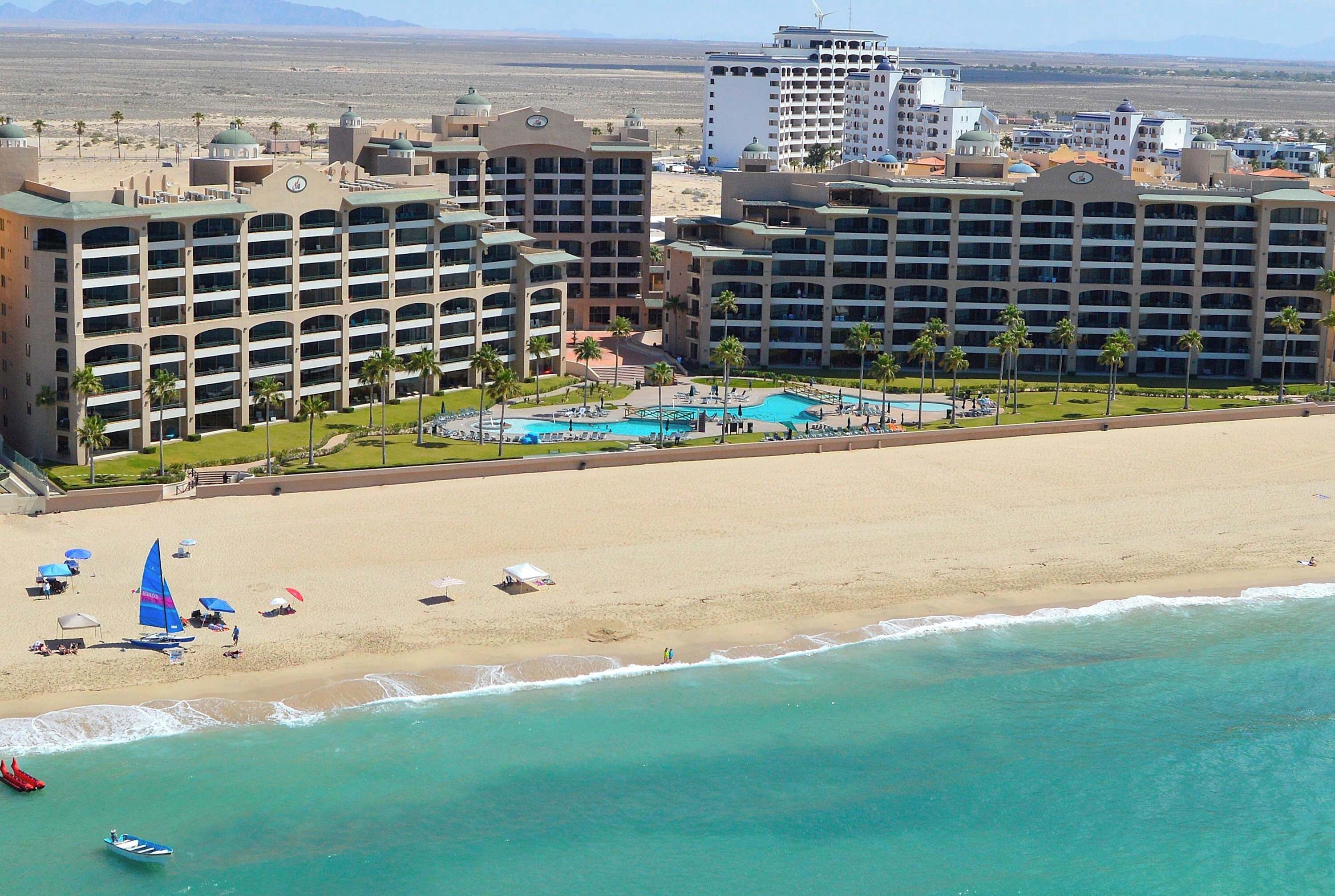 A resort with multiple hotel buildings, a beach, and a swimming pool.