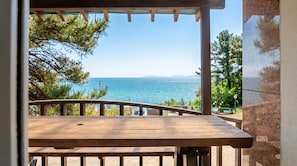 Une terrasse en bois offrant une vue sur la mer et les montagnes.