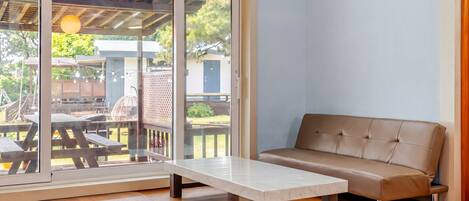 A room with a sliding glass door leading to an outdoor patio area, a sofa, and a small table.