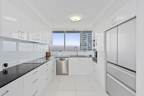 Eine moderne Küche mit weißen Schränken, Edelstahlgeräten und einem großen Fenster mit Blick auf die Stadt.