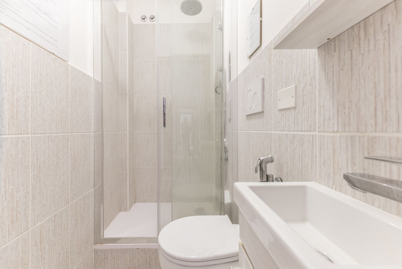 A modern bathroom with a glass-enclosed shower, a white toilet, and a bathtub.