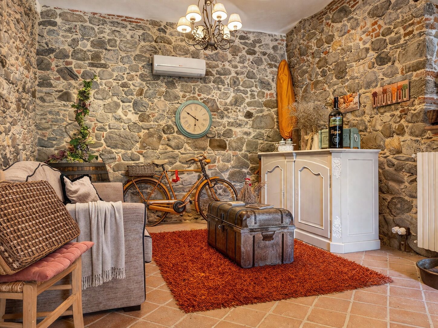 A cozy room with a stone wall, a vintage bicycle, a wooden cabinet, and a red rug.