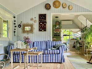 Ein Zimmer mit einem blau-weiß gestreiften Sofa, einem Holztisch und verschiedenen Wanddekorationen, darunter Hüte und ein Spiegel.