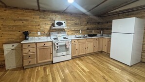 A kitchen with wooden walls, a white stove, a microwave, and a refrigerator. - CountryComfortRetreat!!! 2-bedroom mobile home with AC in Birch Tree (Birch Tree)