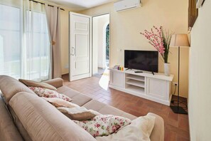 A living room with a sofa, TV, and a plant. - Beautiful apartment near Lucca with pool (Capannori)