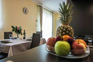 A dining table with a fruit bowl containing a pineapple, apples, strawberries, and oranges. - Beautiful apartment near Lucca with pool (Capannori)