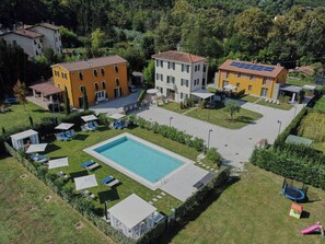 A residential area with a swimming pool, multiple buildings, and outdoor seating areas. - Beautiful apartment near Lucca with pool (Capannori)