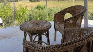Un balcón con mobiliario de mimbre y vistas a un paisaje montañoso.