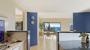 Eine moderne Küche mit Essbereich, einem großen Fenster und Blick sowie einer blauen Akzentwand.