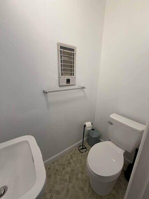 A small bathroom with a toilet, sink, and a ventilation unit on the wall. - 2BR 1.5BA New Condo Near Hospitals - Sleeps 5 (Saint Andrews)