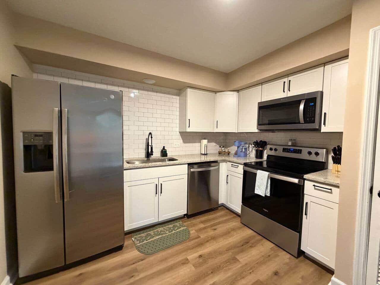 A compact kitchen with a refrigerator, microwave, oven, and dishwasher.