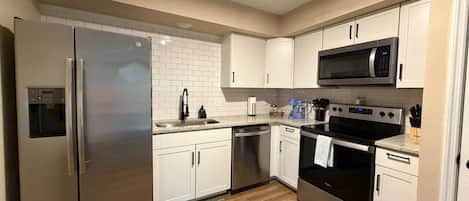 A compact kitchen with a refrigerator, microwave, oven, and dishwasher.