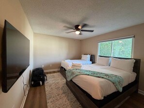 A bedroom with a bed, a ceiling fan, a TV, and a window. - 3BR 1.5BA New Condo Near Hospitals - Sleeps 7 (Saint Andrews)