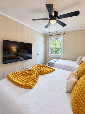 A bedroom with two beds, a ceiling fan, a TV mounted on the wall, and a window with a view of trees. - 3BR 2BA Stylish Condo Near Hospitals - Sleeps 8 (Saint Andrews)