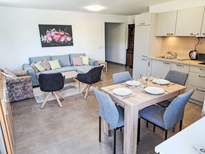 Ein moderner Wohnraum mit Essbereich, Sofa und Küche.