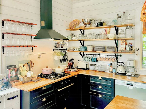 A kitchen with wooden shelves, a stove, and various kitchen utensils. - Pearl of the Prairie (Tollered)
