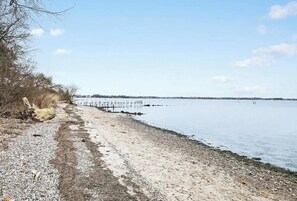 A beach with a wooden pier extending into calm water, surrounded by sparse vegetation and a clear sky. - Cozy beach house with sea view in Gråsten (Gråsten)