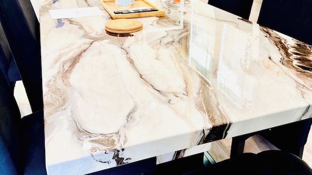 A conference table with a marble finish, surrounded by black chairs, in a room with a white shelving unit and a printer on the wall. - Entire Home with Three Bedroom at the heart of Vancouver (Vancouver)